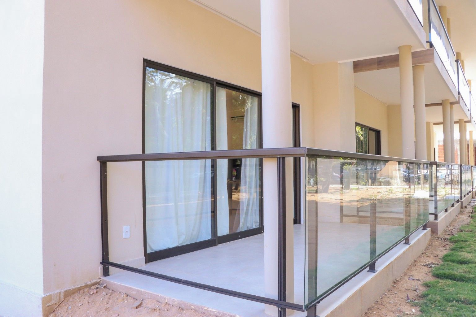 A building with a covered outdoor area featuring glass railings and large windows.