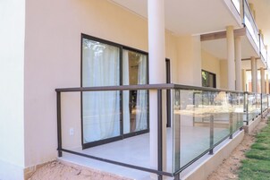 Un edificio con un área exterior techada, barandas de vidrio y ventanas grandes.