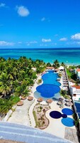 Un resort con varias piscinas, palmeras y vistas al océano.