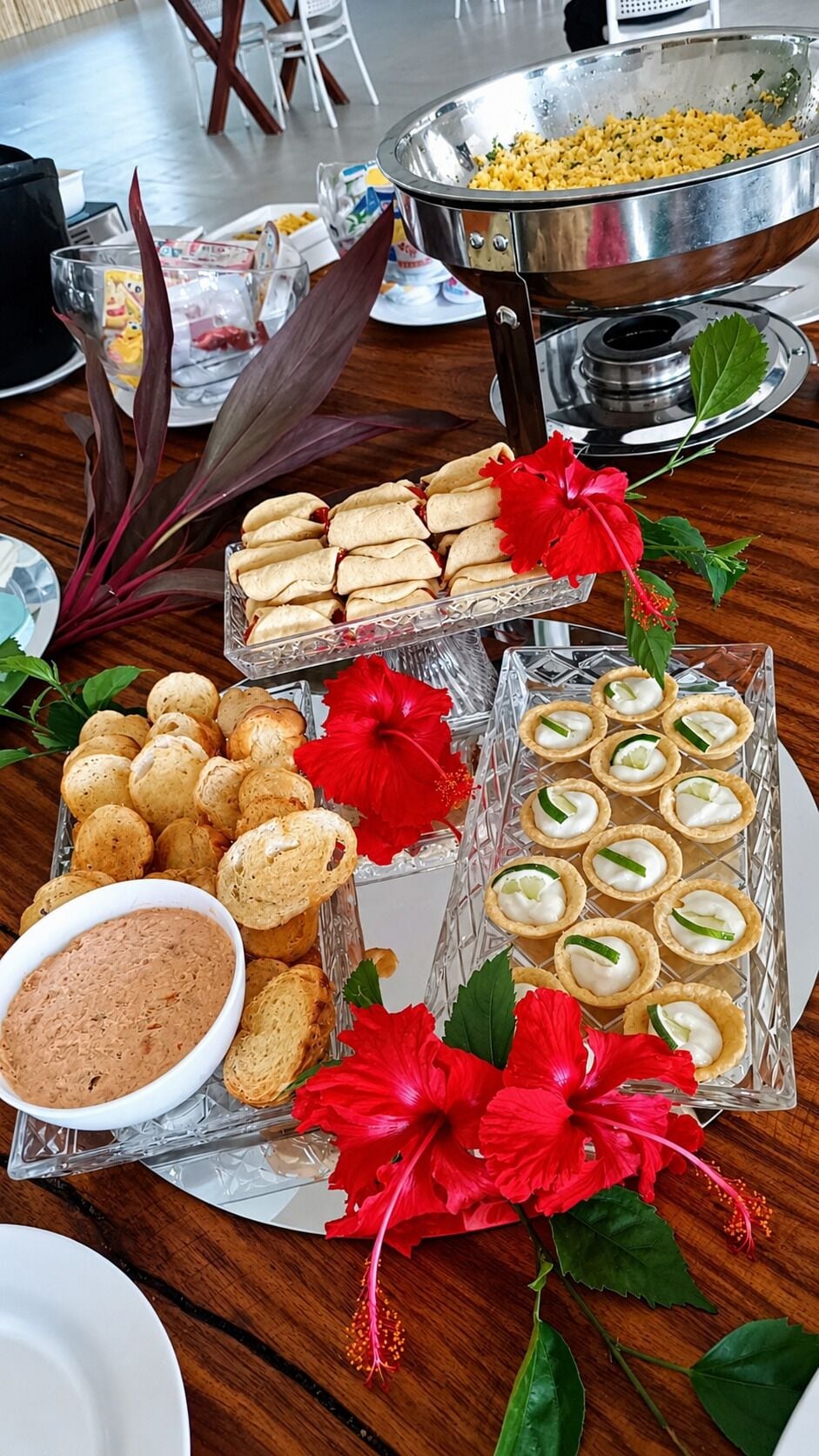A buffet table with various food items, including a bowl of dip, bread rolls, and small pastries.
