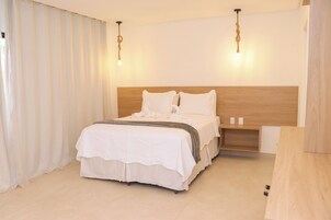 Un dormitorio ordenado con una cama grande, cabecera de madera y una mesita de noche.