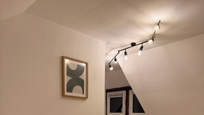 Et soveværelse med to senge, en loftlampe og et indrammet abstrakt billede.