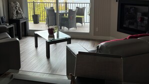 Una sala de estar con chimenea, un televisor grande y vistas a un lago y montañas a través de puertas corredizas de vidrio.
