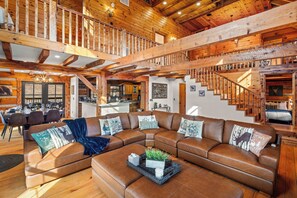 A spacious living area with a large sectional sofa, wooden beams, and a staircase. - LogRhythm Ultra Luxury 48Acre, 7Bed/6.5Bath estate (Massanutten)