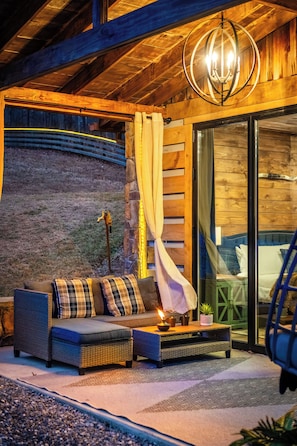 A cozy outdoor seating area with a sofa, cushions, and a table with a candle. - LogRhythm Ultra Luxury 48Acre, 7Bed/6.5Bath estate (Massanutten)