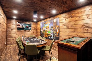 Une pièce en bois avec une table de poker, des chaises et un tableau accroché au mur.
