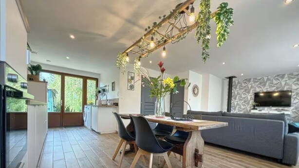 A modern kitchen with a dining area, a grey sofa, and a TV in the living room. - Gîte marais Audomarois, pedestrian/boat access (Tilques)
