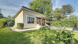 A single-story house with a covered porch, a small garden, and a well-maintained lawn. - Gîte marais Audomarois, pedestrian/boat access (Tilques)