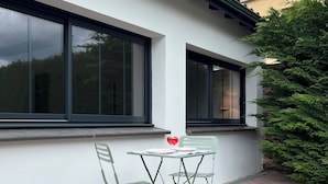 Un patio con una mesa y sillas, baranda metálica verde y un ventanal grande.