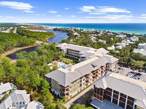 An aerial view of a coastal resort with multiple buildings, a marina, and a river. - Lazy Duck Retreat, Red Fish Village Private Beach Access, Resort Amenities (Santa Rosa Beach)