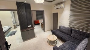 Een moderne woonkamer met een grijze bank, een ronde salontafel en een kroonluchter.