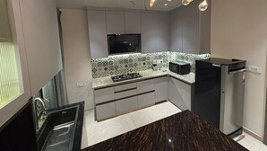 Een moderne keuken met een donker marmeren aanrecht, een ingebouwde kookplaat en een zwarte koelkast.