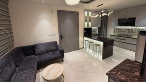 Een moderne woonkamer met een modulaire bank, een ronde salontafel en een keukenbar met een barkruk.