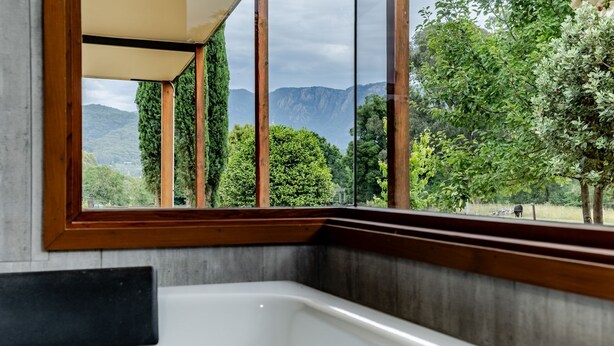 A bathroom with a large window, wooden frame, and a bathtub. - Buffalo Bliss - Magical views (Porepunkah)