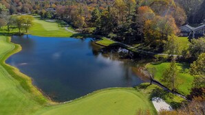 A golf course with a lake, surrounded by autumn-colored trees and a hill in the background. - Cozy Mountain Cottage Near Downtown (Highlands)