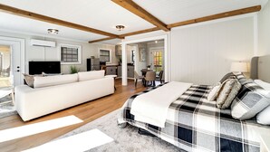 A spacious room with a large bed, a sofa, and a kitchen area. - Cozy Mountain Cottage Near Downtown (Highlands)