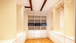 A walk-in closet with white shelving and wooden flooring. - Fachwerk Boutique Hotel by corents (Hattingen)