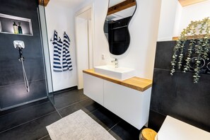 A modern bathroom with a shower, a sink, and a mirror. - Fachwerk Boutique Hotel by corents (Hattingen)