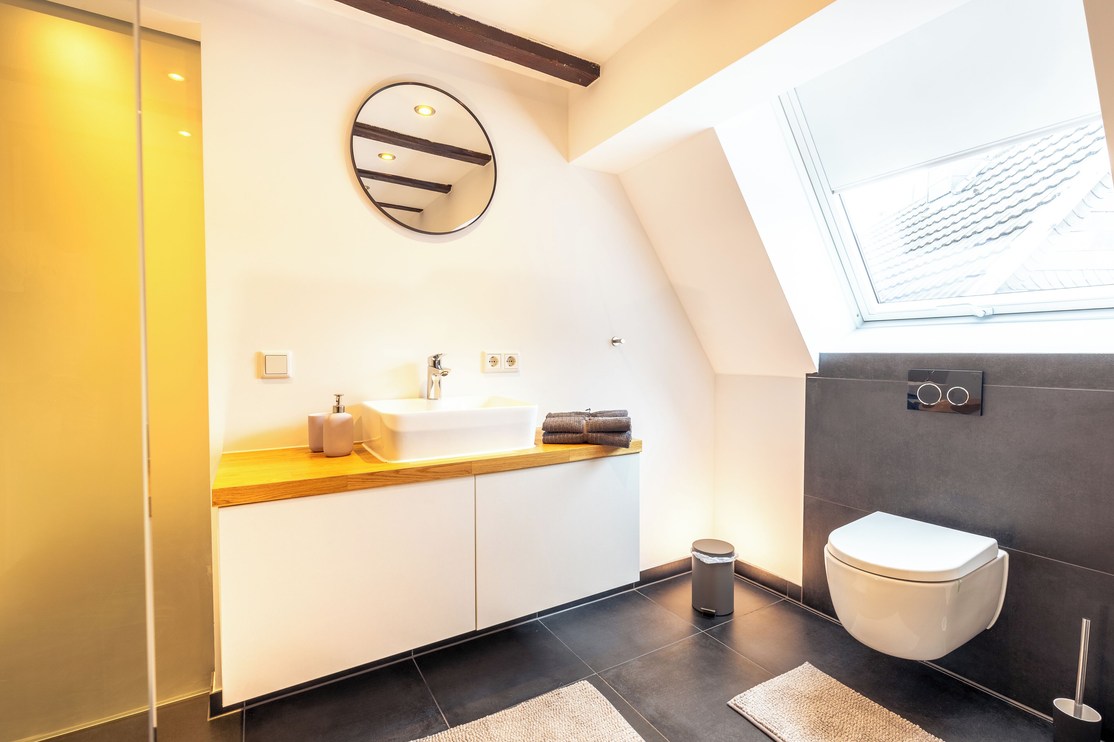 Ein modernes Badezimmer mit Waschbecken, Spiegel, Toilette und Fenster.