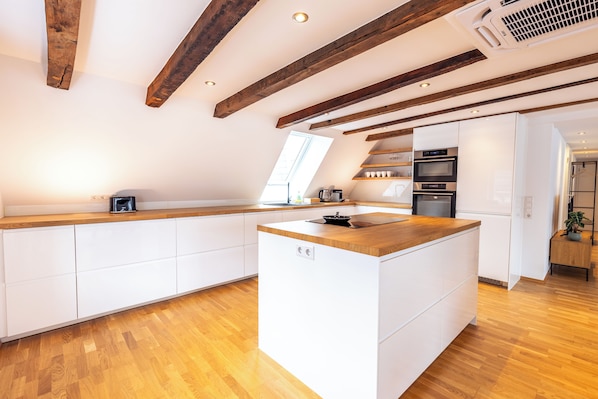 Una cocina moderna con vigas de madera, armarios blancos y una isla central.