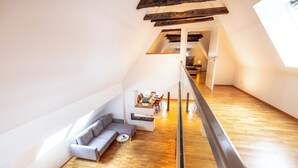 A modern loft with a wooden floor, a gray sofa, and a dining area with a table and chairs. - Fachwerk Boutique Hotel by corents (Hattingen)