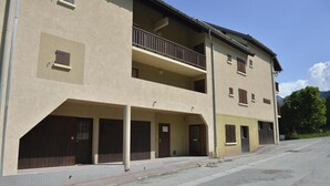 A two-story building with a balcony on the second floor, a covered entrance, and a parking lot in front. - 1st floor, balcony, parking, 25m², Valloire (Valloire)