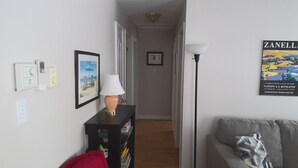 A hallway with a lamp, a framed picture, and a poster on the wall.