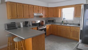 A kitchen with wooden cabinets, a stainless steel refrigerator, a microwave, a stove, and a coffee maker.