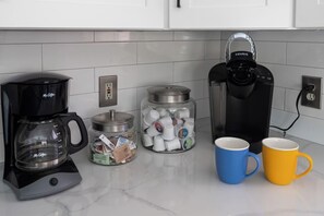 A kitchen with a coffee maker, a Keurig coffee machine, a jar of coffee pods, and two mugs. - Modern Oasis, Heated Pool & Spa (Phoenix)