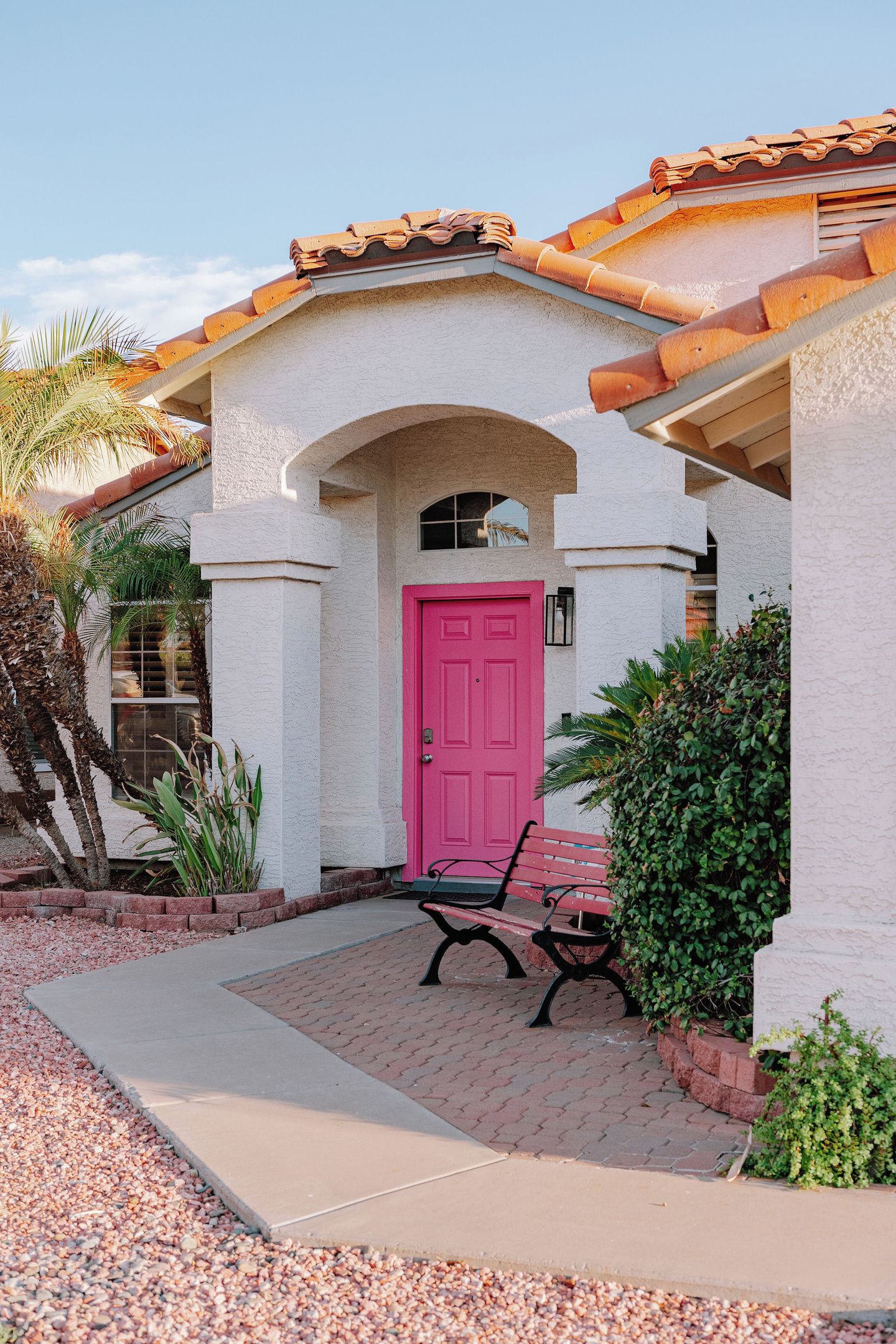 A building with a red door, a bench, and a tiled roof.