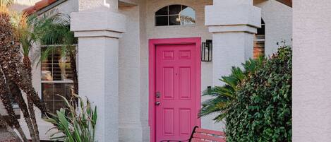 A building with a red door, a bench, and a tiled roof.