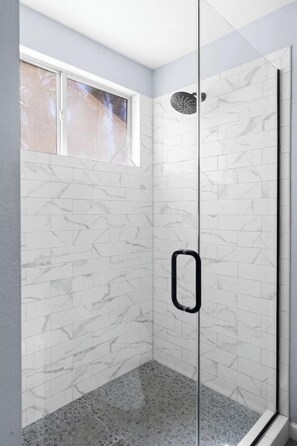 A walk-in shower with white marble tiles and a glass door. - Modern Oasis, Heated Pool & Spa (Phoenix)