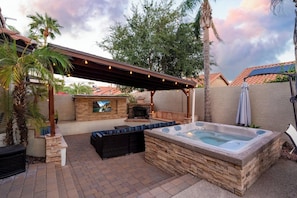 A backyard with a hot tub, outdoor seating, a fireplace, and a pergola with string lights. - Modern Oasis, Heated Pool & Spa (Phoenix)