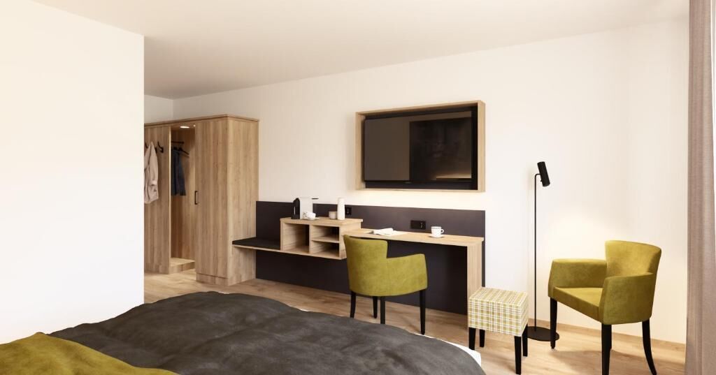 Een moderne slaapkamer met een bed, een bureau, twee stoelen, een kledingkast en een nachtkastje.