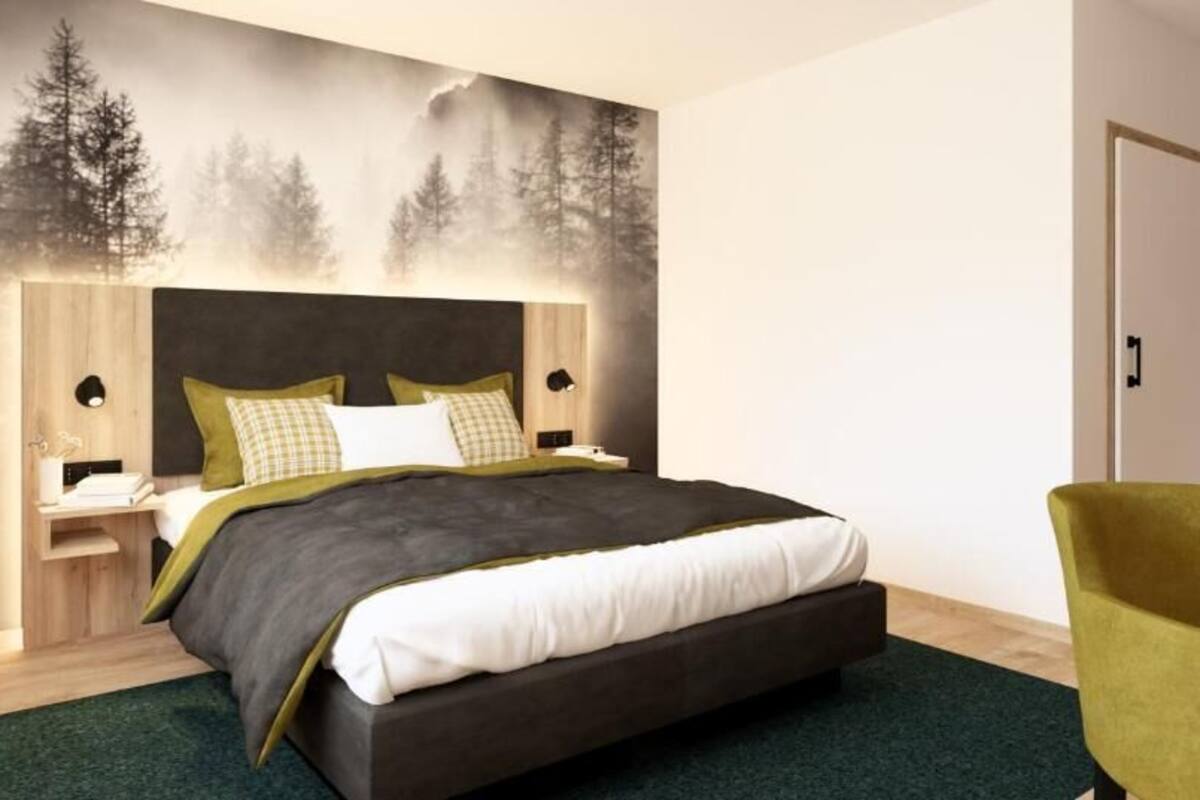 Un dormitorio moderno con una cama grande, una mesita de noche, una silla y un mural de árboles en la pared.