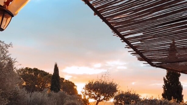 Area piscina con patio in pietra, una pergola e alberi sullo sfondo.