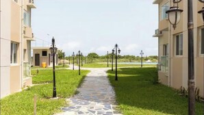 A pathway leading to a building with a tiled floor and lamp posts. - Luxurious Getaway: 24/7 Security - Pool - Balcony! (Sakumono)