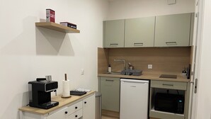 Et kompakt køkken med kaffemaskine, opvaskemaskine og mikrobølgeovn.