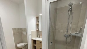 Et moderne badeværelse med toilet, vask og brusebad.
