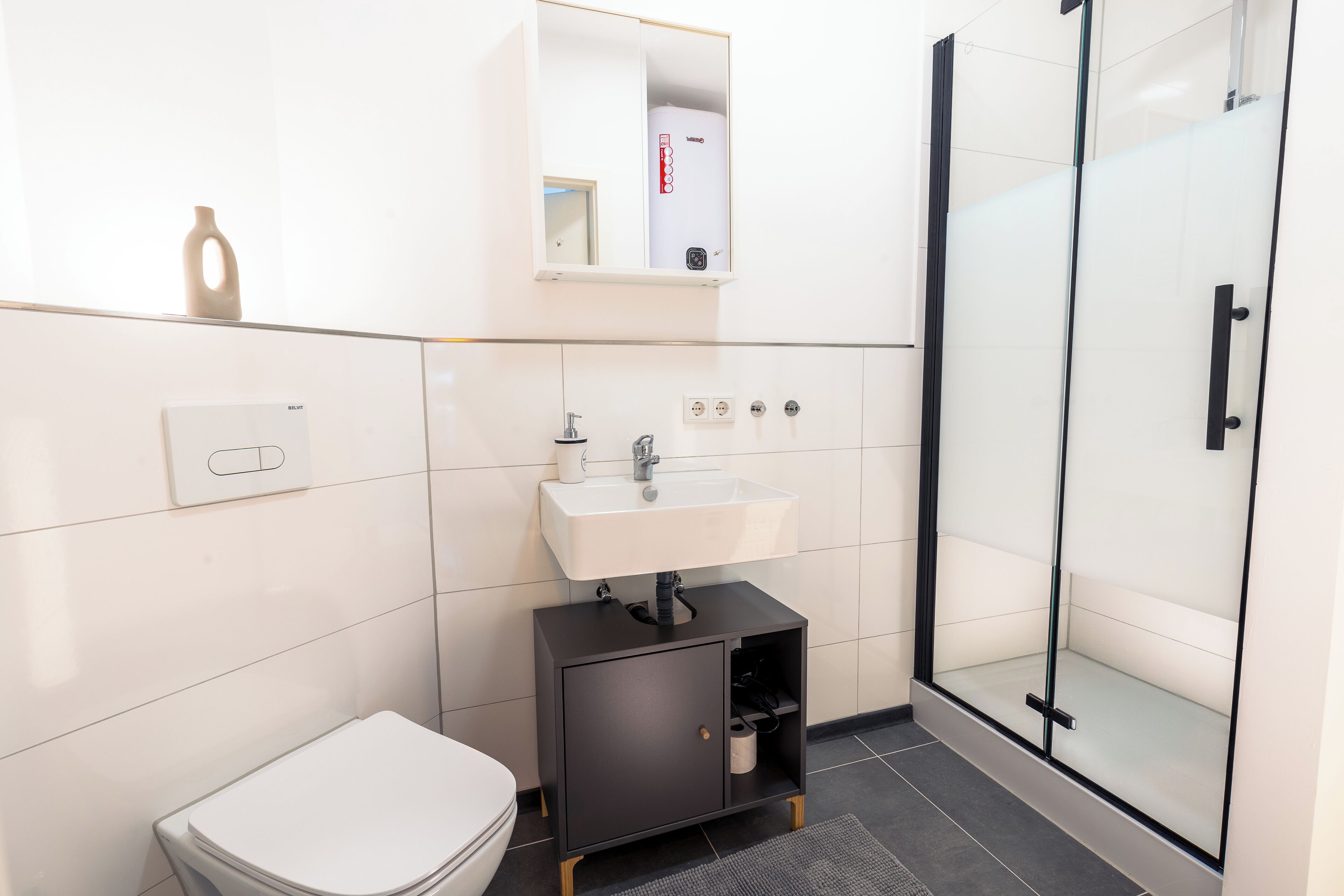 Een moderne badkamer met toilet, wastafel en douchecabine met glazen wanden.