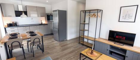 A modern living space with a dining area, kitchenette, and entertainment unit.