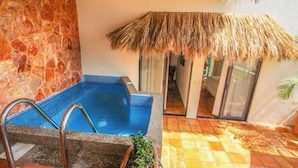 A swimming pool with a stone wall and a thatched roof structure.