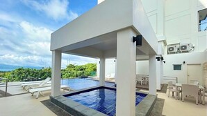A modern pool area with lounge chairs and a clear view of the ocean.