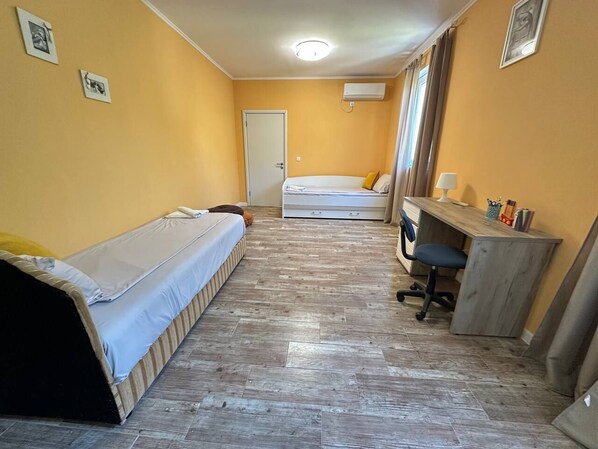 Une chambre de taille modeste, équipée de deux lits, d’un bureau et d’une chaise.