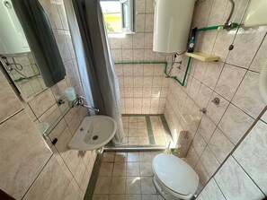 A small bathroom with a toilet, sink, and shower area. - Ceres  Apartments (Utjeha)