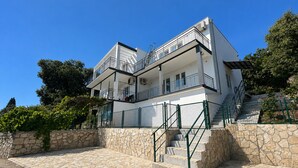 A multi-story building with balconies, stone steps, and a stone wall. - Ceres  Apartments (Utjeha)