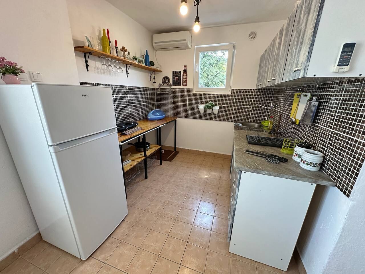 A compact kitchen with a refrigerator, a sink, and a window.