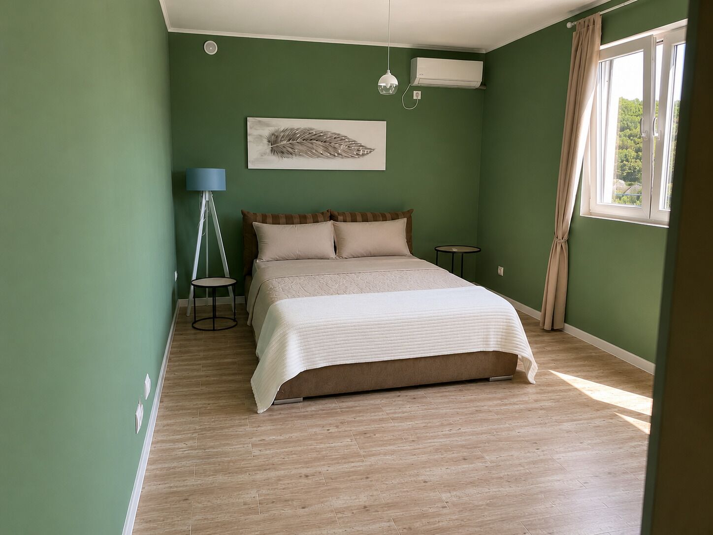 A bedroom with a bed, a lamp, a small table, and a window with curtains.