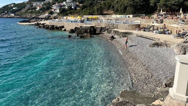 A coastal area with clear water, a pebble beach, and buildings in the background. - Ceres  Apartments (Utjeha)