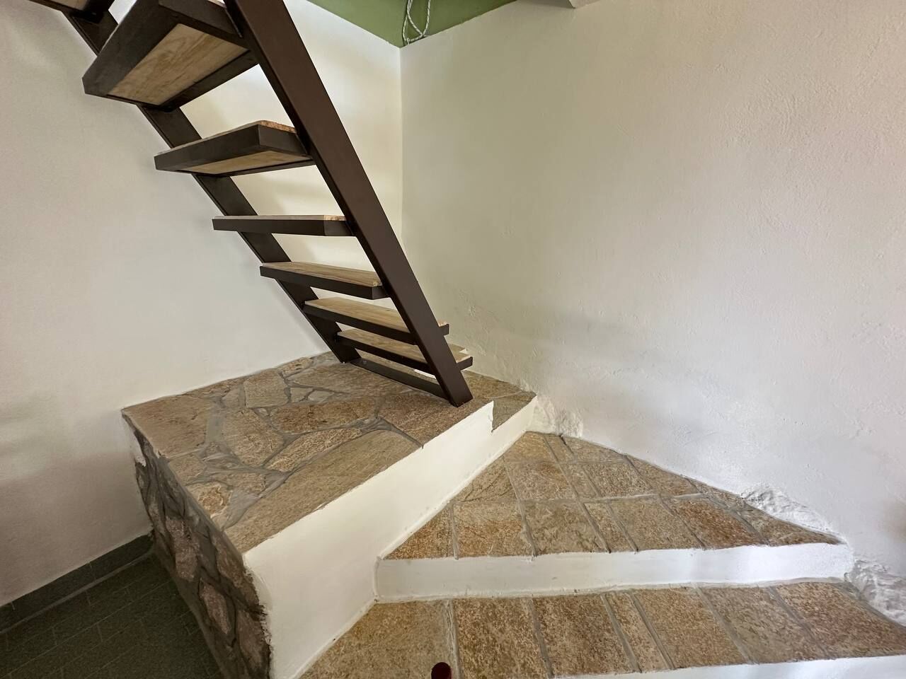 A staircase with a wooden handrail and stone steps.
